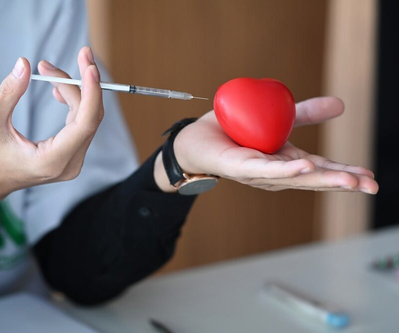 doctor holding red heart and syringe